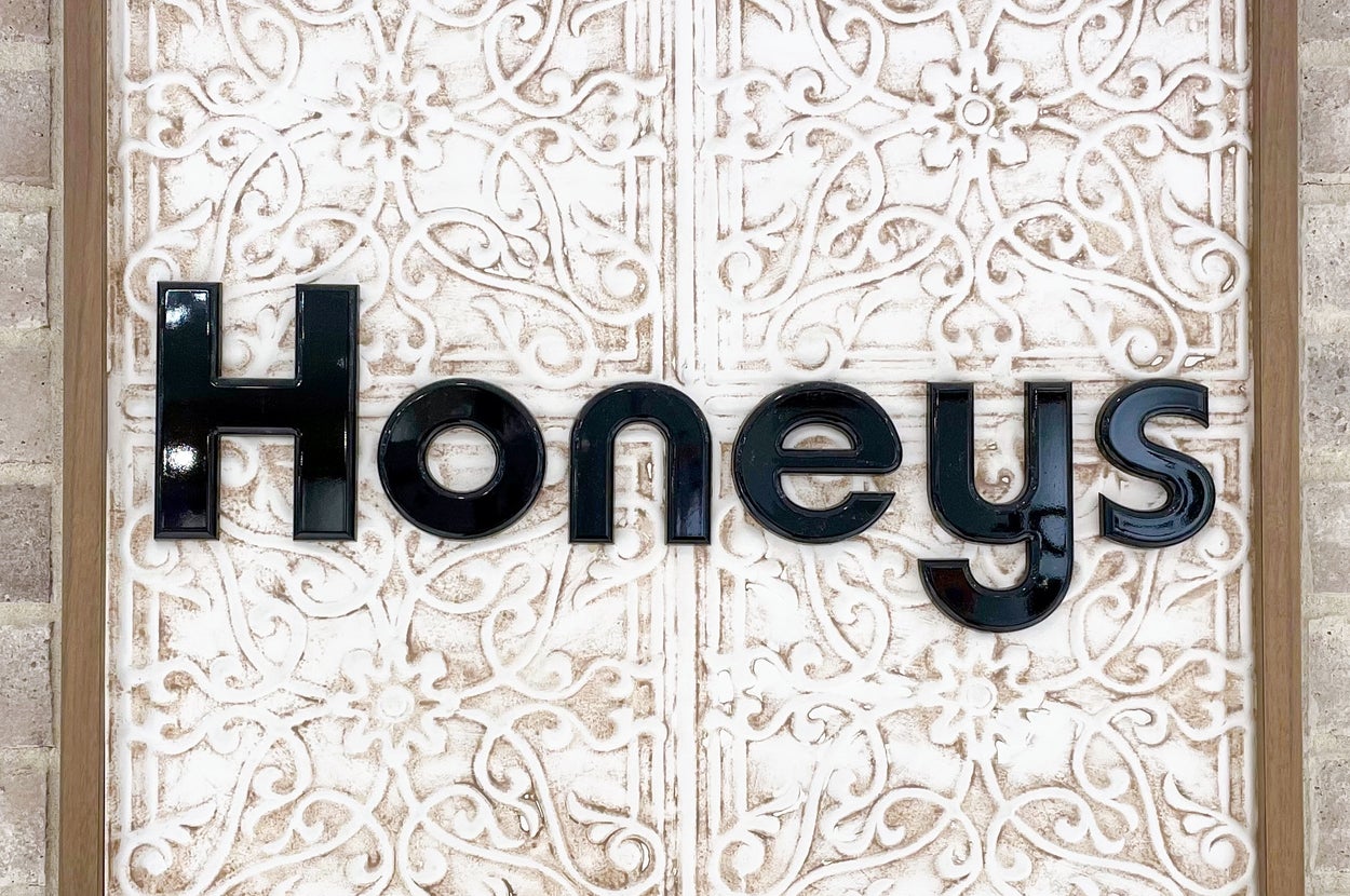 レンガ壁に「Honeys」と書かれた装飾的な看板が設置されている。