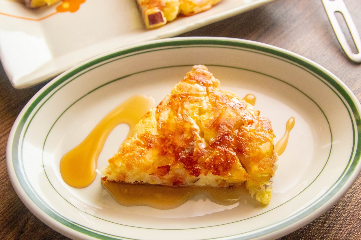 皿にのった一切れの料理(お好み焼き風)が置かれ、ソースがかかっている。後ろに同じ料理全体の皿が見える。