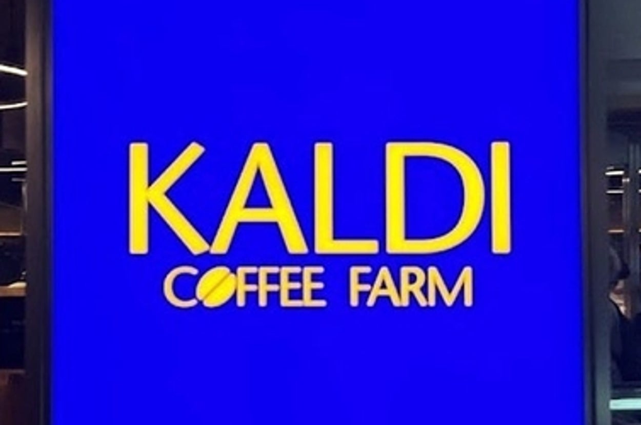 カルディコーヒーファームの看板、店内の様子が薄く透けて見える。