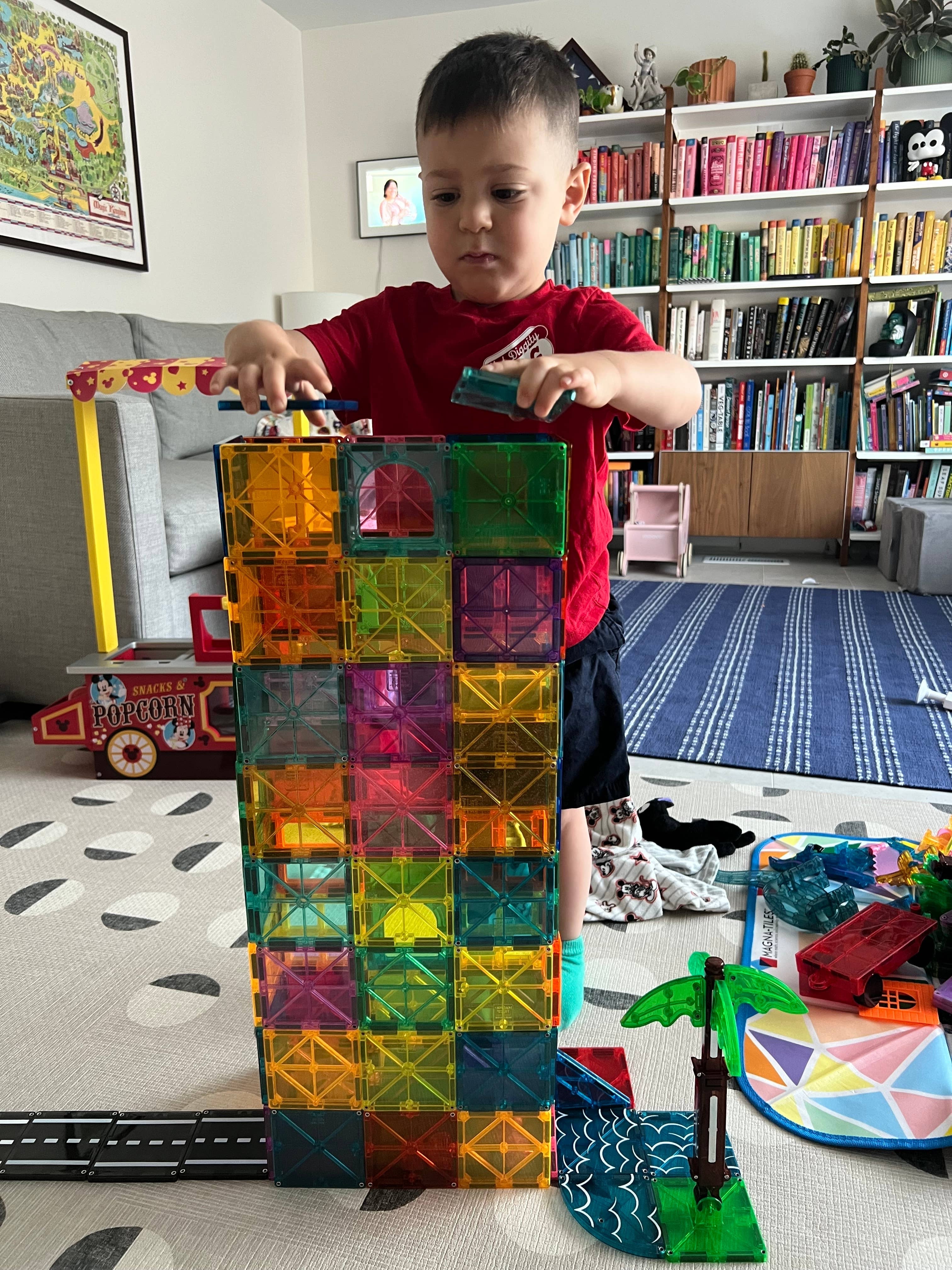 Child gathering  a gangly  operation    with colorful magnetic tiles successful  a playroom