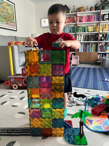 Child gathering a gangly operation with colorful magnetic tiles successful a playroom