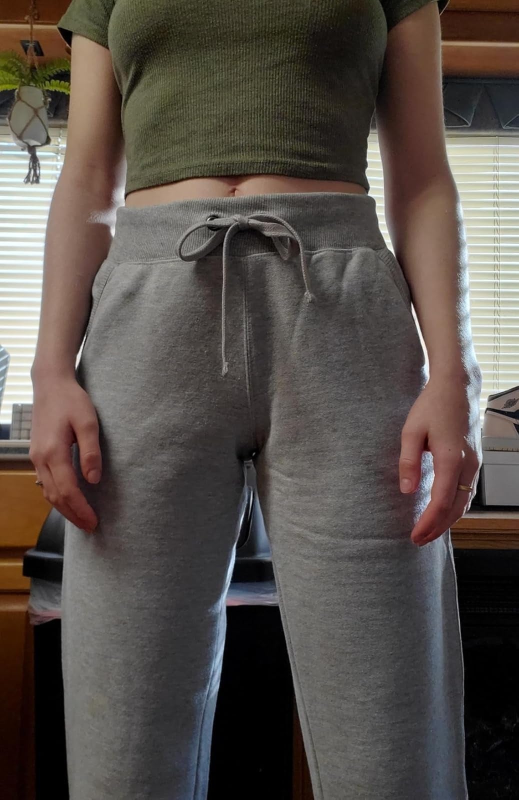 Person wearing grey  sweatpants with a drawstring and a cropped top, lasting  indoors successful  beforehand   of a window