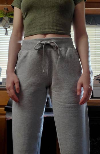 Person wearing grey sweatpants with a drawstring and a cropped top, lasting indoors successful beforehand of a window
