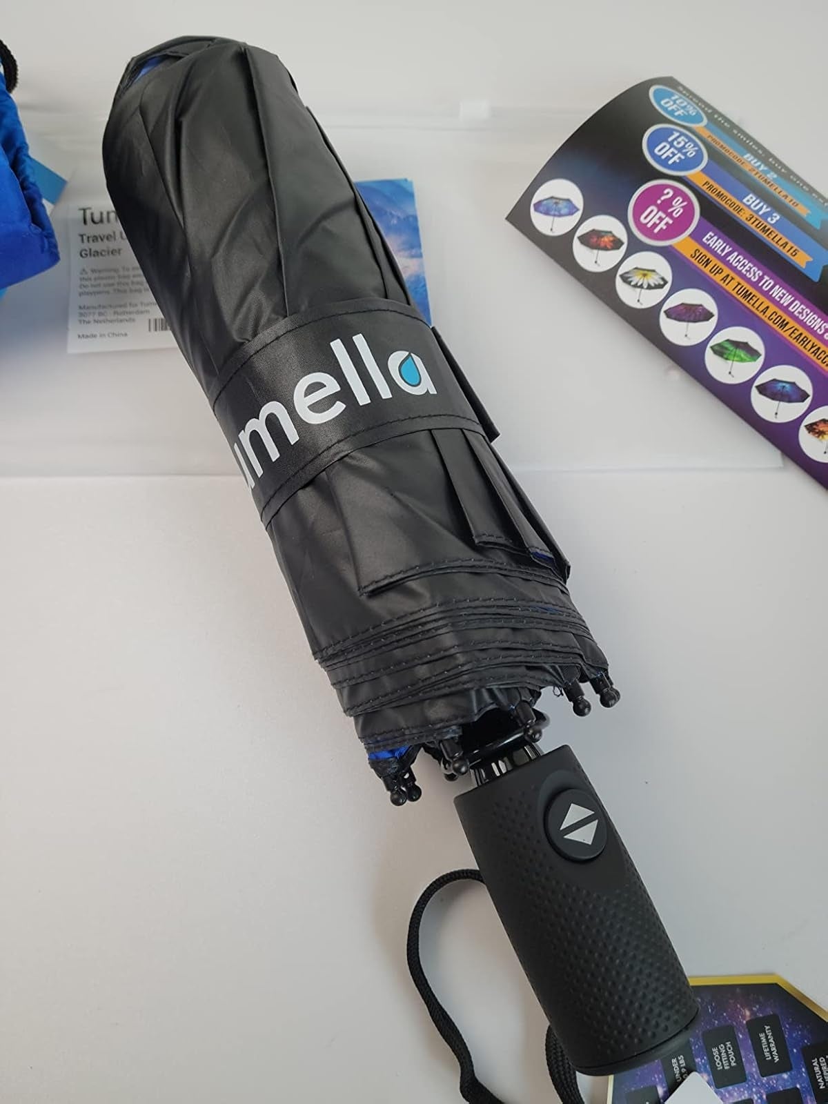 Folded achromatic  umbrella with a textured grip  connected  a array  adjacent   brochures showcasing assorted  products and discounts
