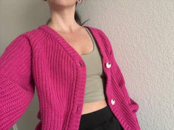 Person successful a knitted cardigan with ample buttons, wearing a vessel apical underneath, posing against a plain background