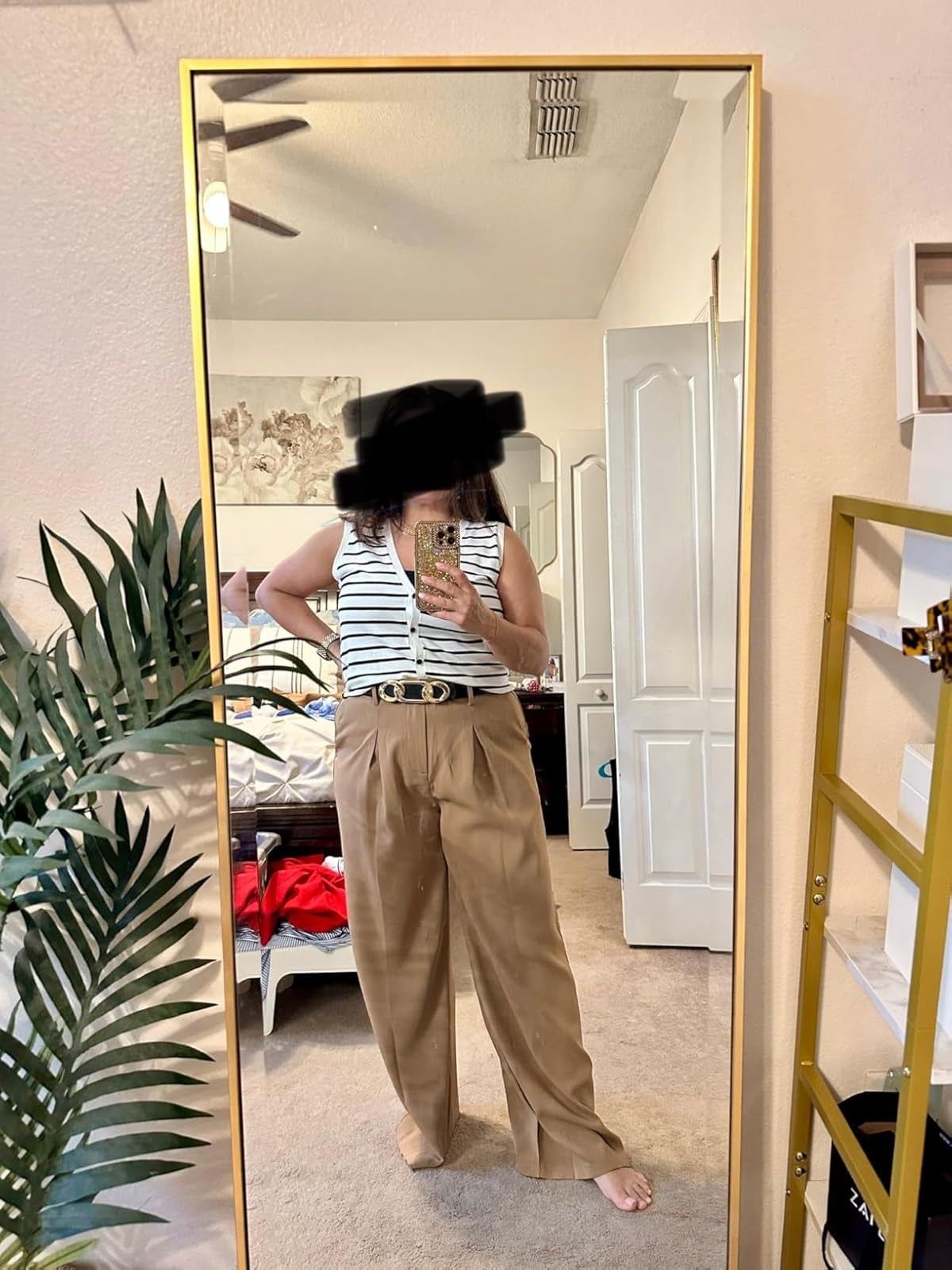 Person taking a reflector  selfie successful  a striped apical  and wide-leg beige pants successful  a chamber  setting