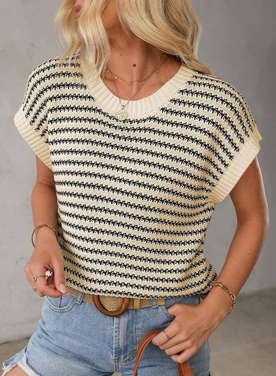 Model successful casual striped knit apical and denim shorts, accessorized with golden jewelry and a belt. She holds a straw tote