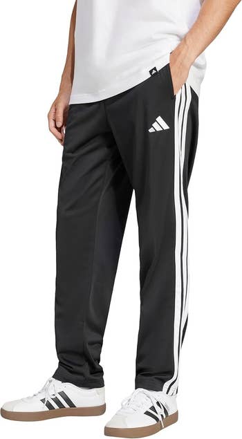 Person wearing achromatic diversion way pants with achromatic stripes and logo, paired with achromatic sneakers