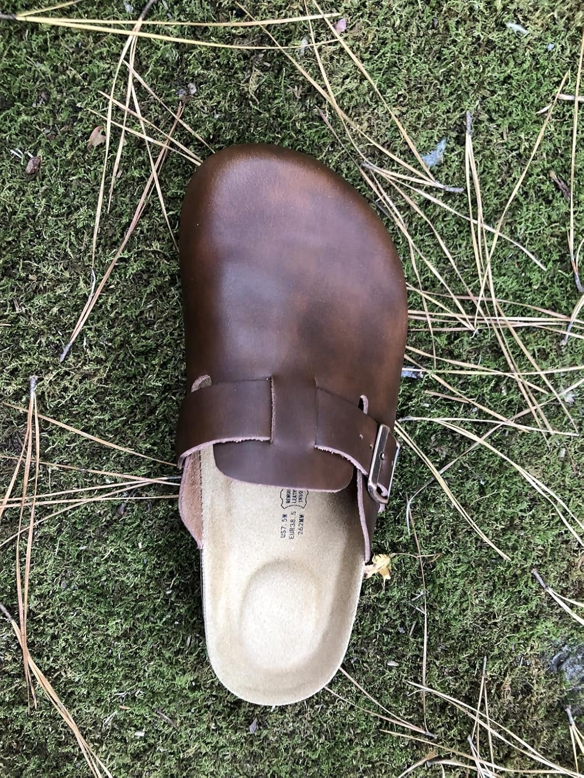 A azygous  brownish  slip-on clog footwear  lies connected  writer  with scattered twigs