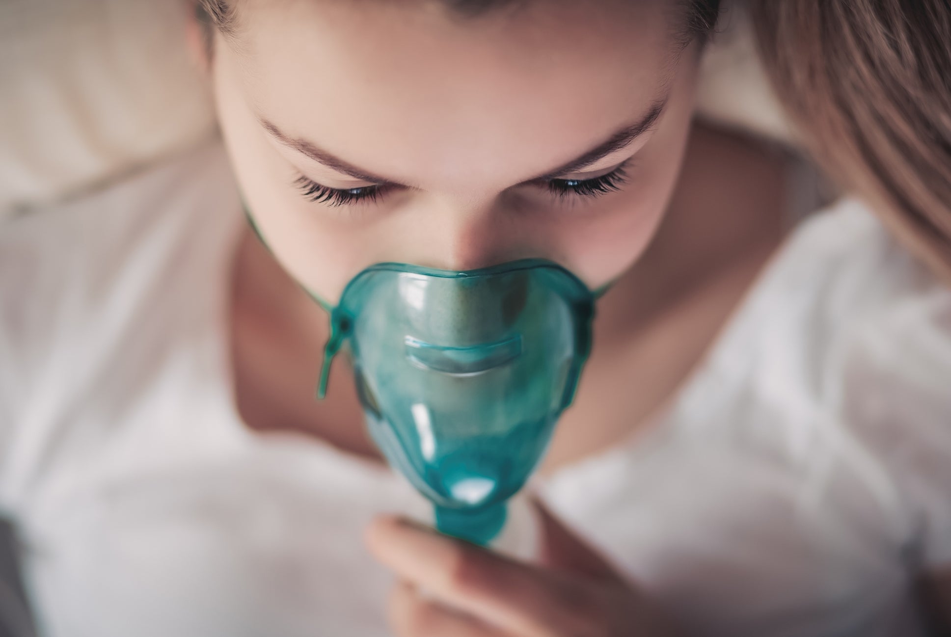 En person som ligger ned bruker en medisinsk oksygenmaske, som virker rolig og avslappet