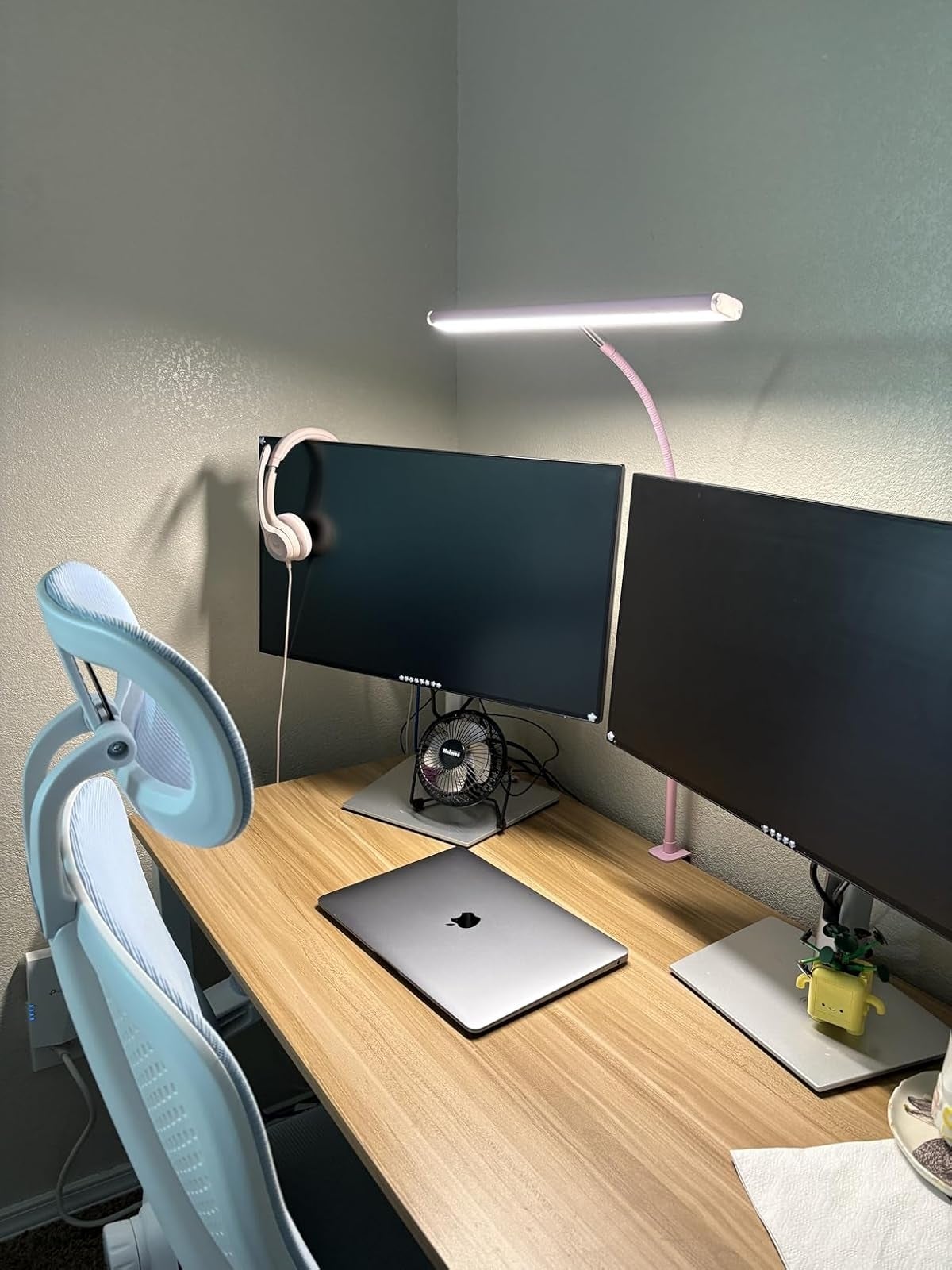 Minimalist location  bureau   setup with dual monitors, laptop, table  lamp, headphones, and an ergonomic chair. Suitable for productivity and comfort
