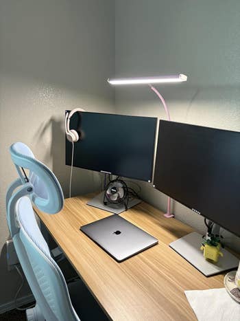 Minimalist location bureau setup with dual monitors, laptop, table lamp, headphones, and an ergonomic chair. Suitable for productivity and comfort