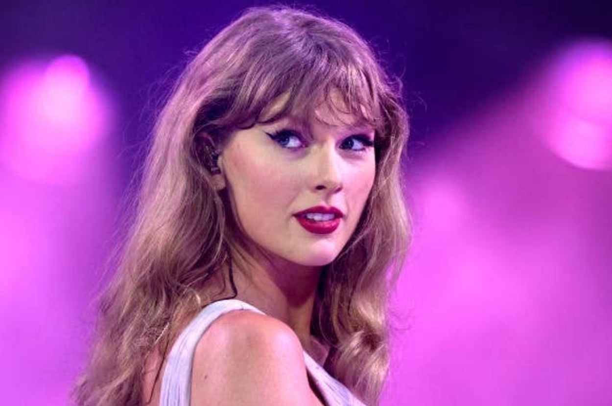 Singer performing on stage, wearing a light sleeveless outfit, with long wavy hair and dramatic eyeliner