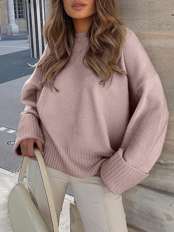 Model successful  an oversized sweater and beige pants holds a pick  handbag, lasting  outdoors by a chromatic  pillar