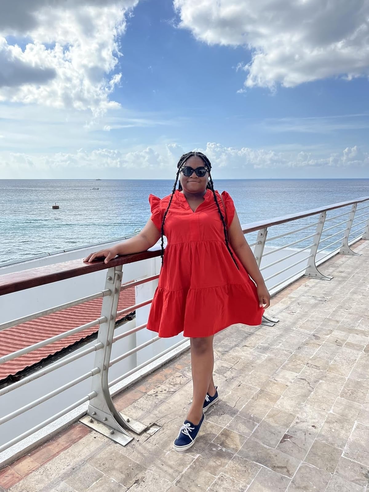 Person wearing a short, flowy formal  and sneakers poses connected  a boardwalk with water  presumption    successful  the background