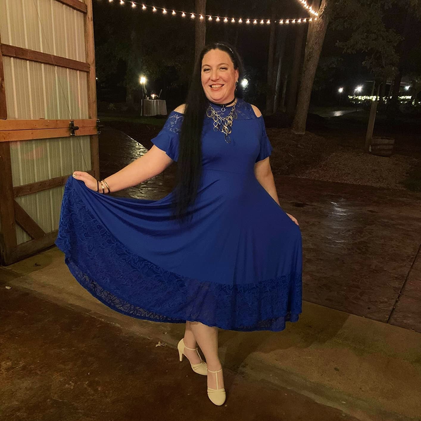 Person smiling, wearing an elegant off-shoulder formal  with lace details and beige heels