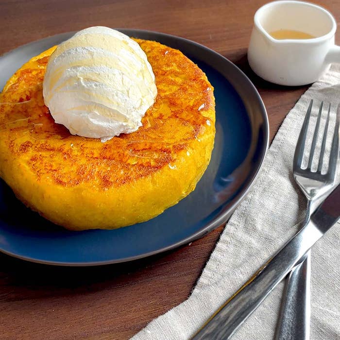 大きなケーキの上にアイスクリームが載っており、横にフォークとナイフが配置されています。