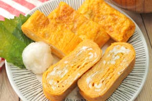 お皿に盛られた玉子焼きと大根おろしが添えられている日本の朝食。