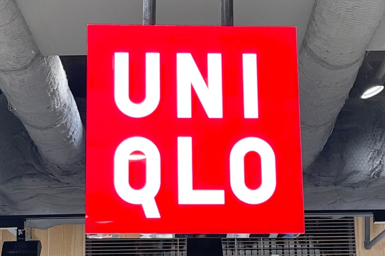 Uniqlo store interior with a prominent logo sign and shelves displaying neatly folded clothing items with price tags