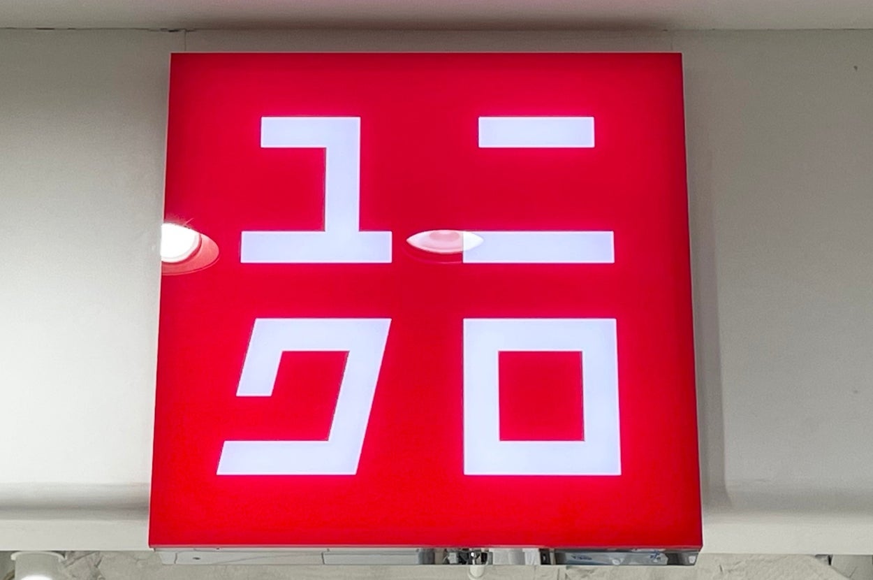 A sign with stylized Japanese characters, resembling a logo, displayed on a red background above a store entrance