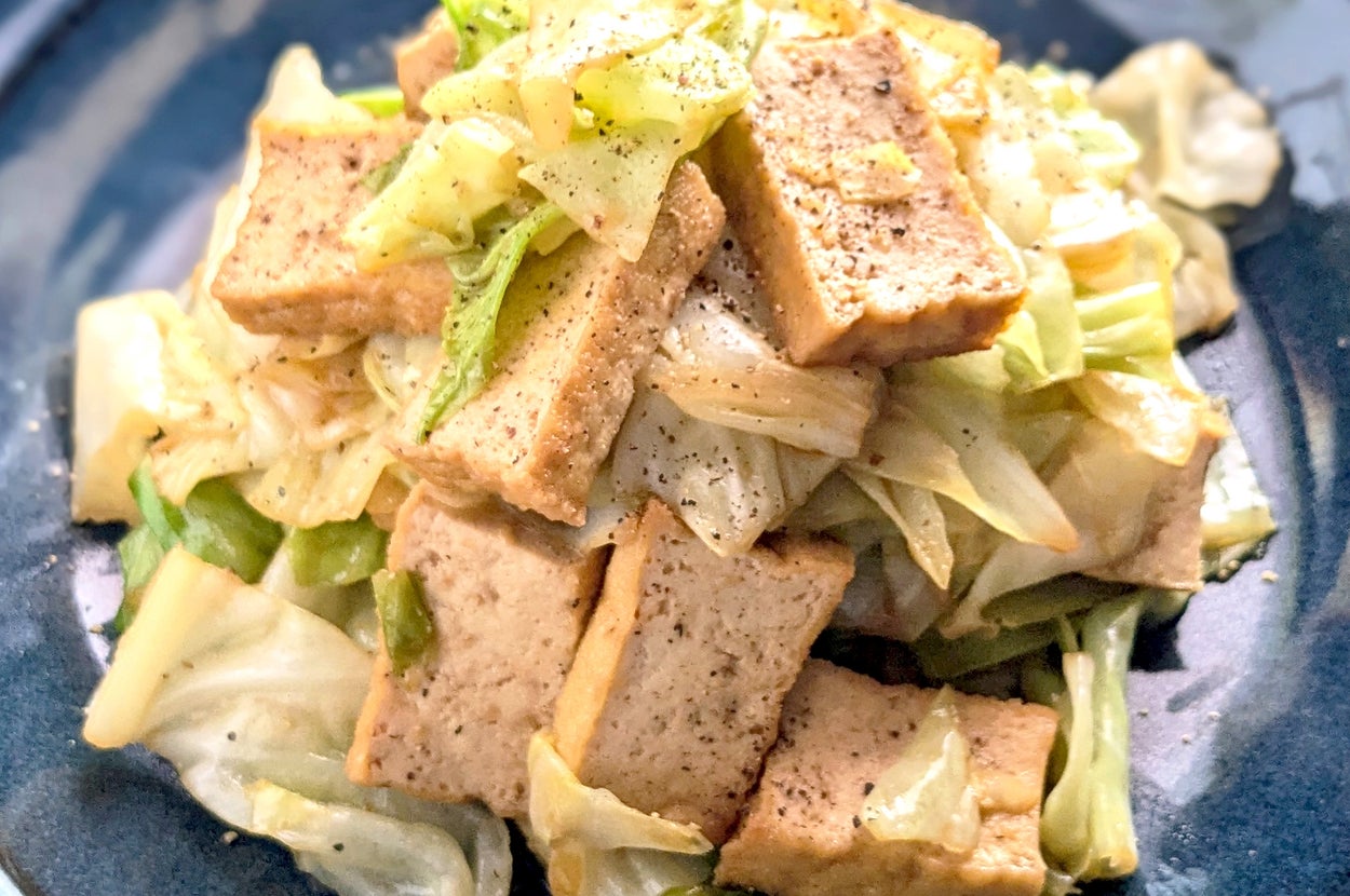 キャベツと厚揚げの炒め物が皿に盛られている。シンプルかつ家庭的な和風料理。