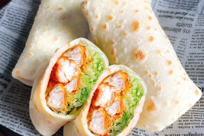 トルティーヤに包まれたチキン、レタスのラップ。半分にカットされたラップが2つの具材を見せています。