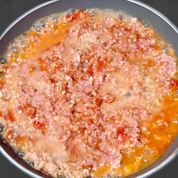 トマトとひき肉がフライパンで加熱されている様子。