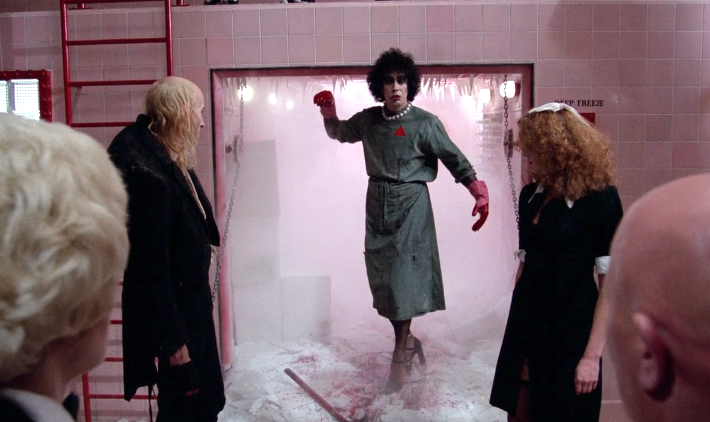 A person in theatrical attire emerges from a mist-filled chamber, surrounded by onlookers in a dramatic scene