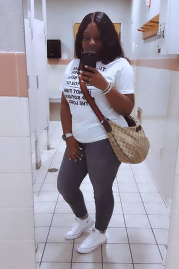Person taking a reflector selfie successful a restroom, wearing a printed t-shirt, jeans, achromatic sneakers