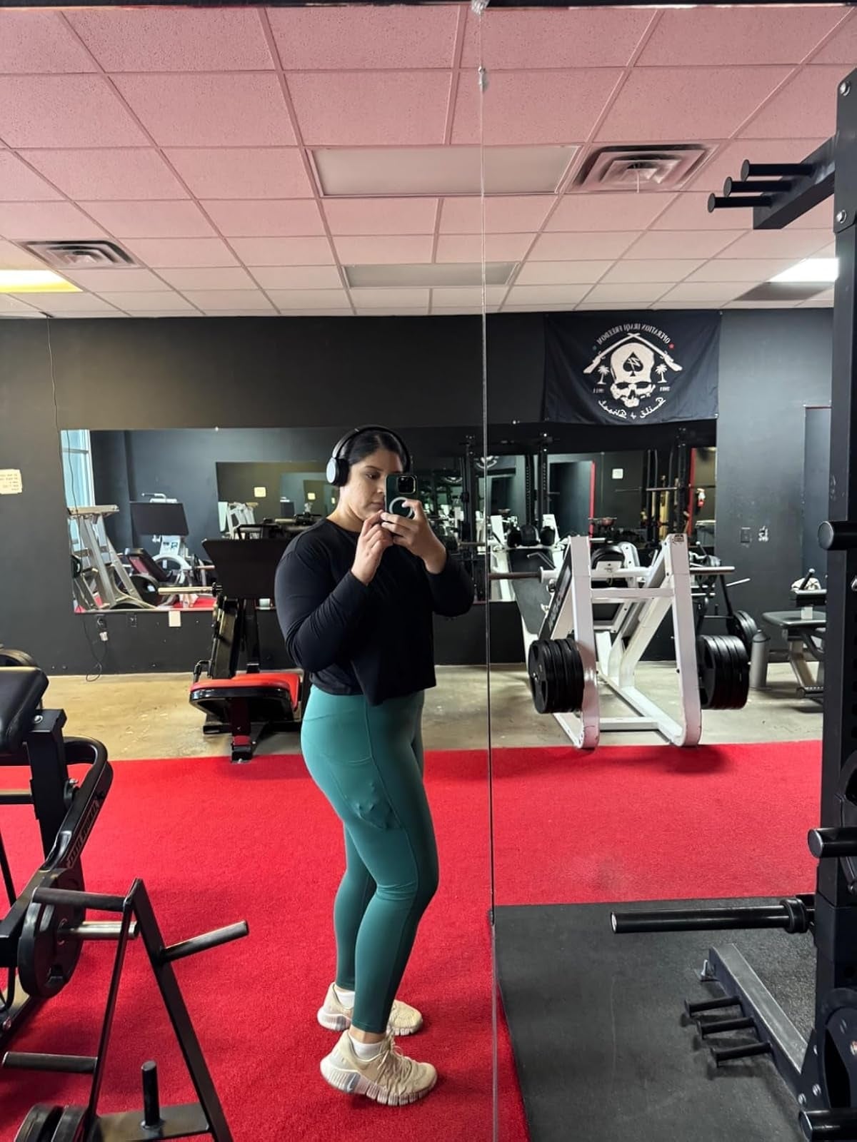 Person successful  a gym wearing headphones, a achromatic  top, and greenish  leggings