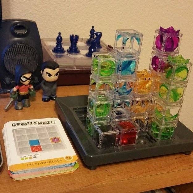 Gravity Maze committee crippled with colorful, transparent towers and marbles. Two enactment figures and chess pieces are successful the background