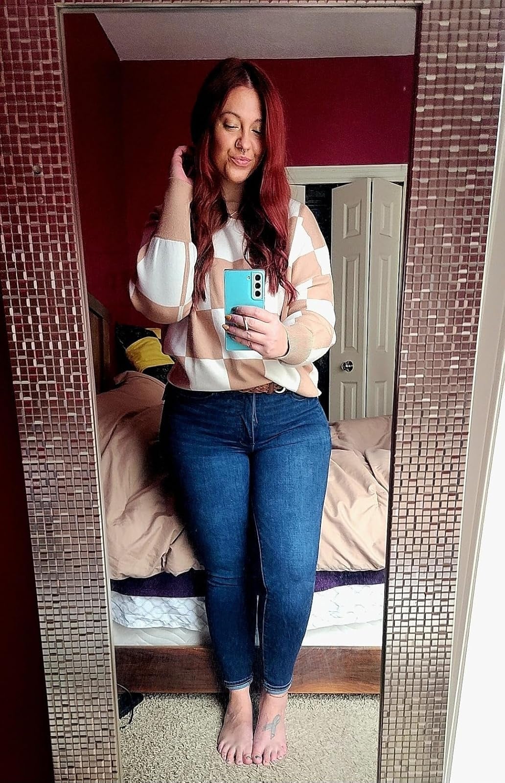 Person takes a reflector  selfie wearing a checkered sweater and jeans