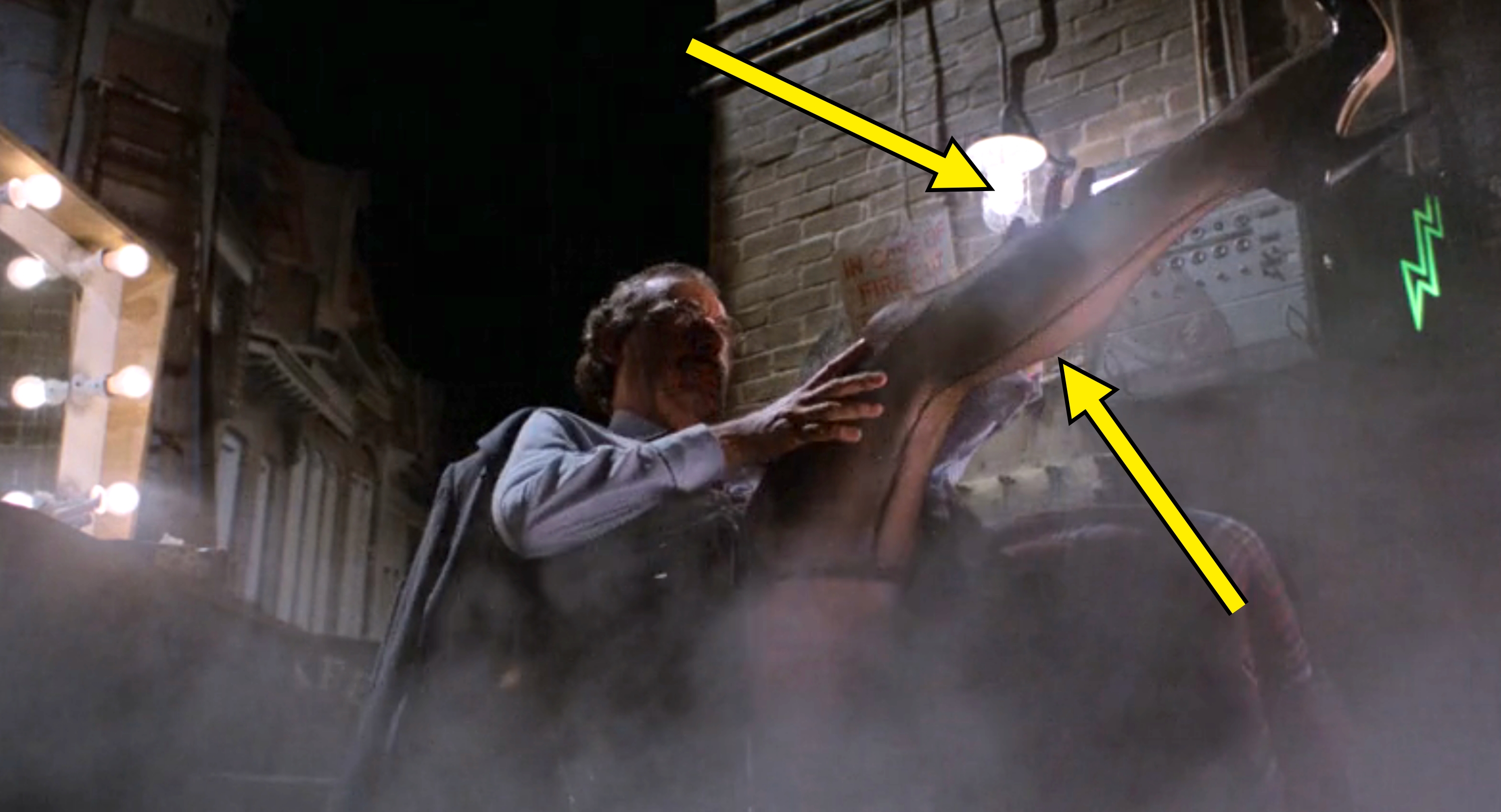 A man on stage lifts a leg under dramatic lighting and smoke, conveying a theatrical performance or backstage scene