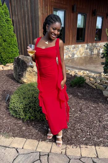 Person posing outdoors successful a sleeveless, tiered formal holding a drink, smiling