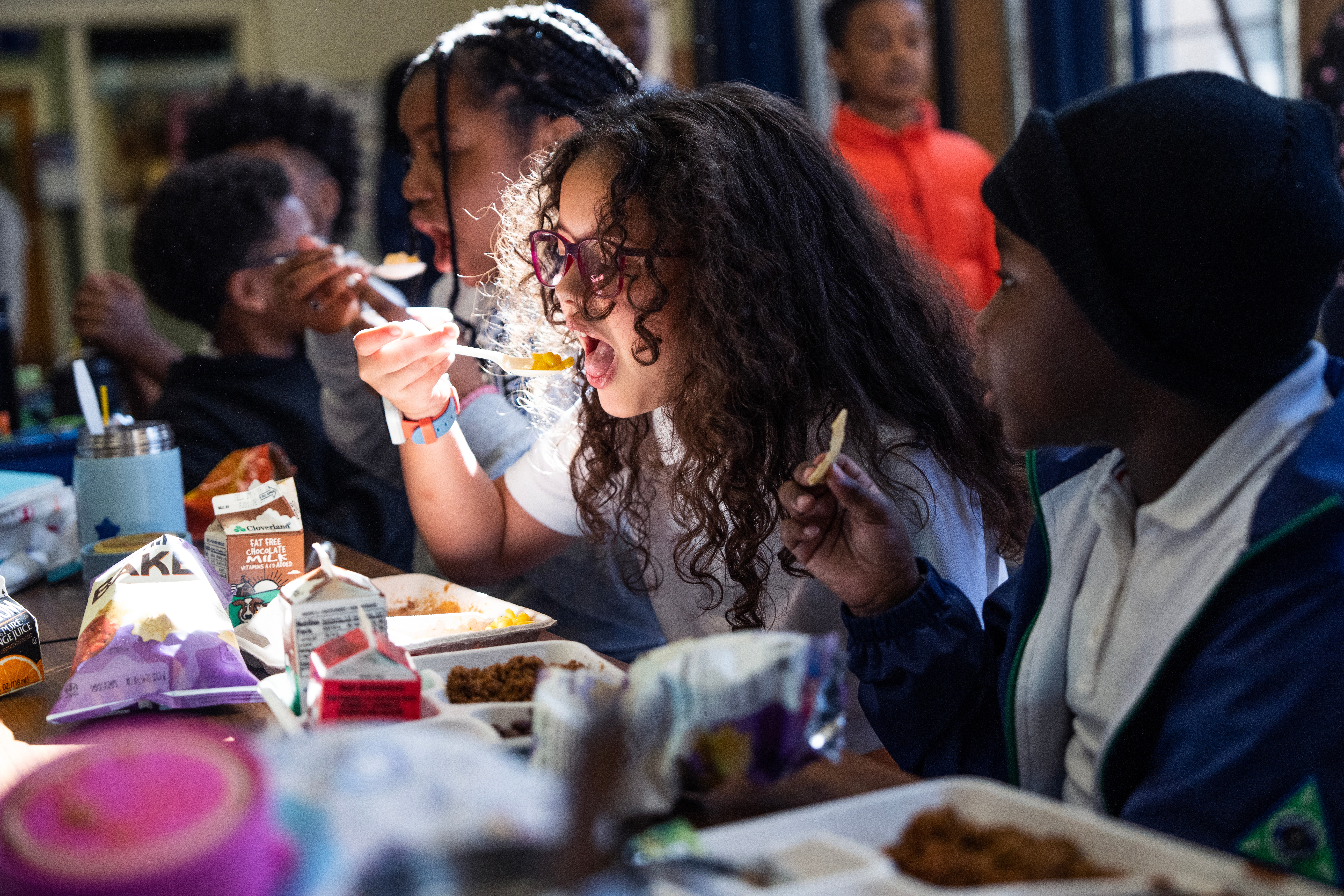 Barn sitter ved et bord i en kafeteria og nyter lunsjen sammen