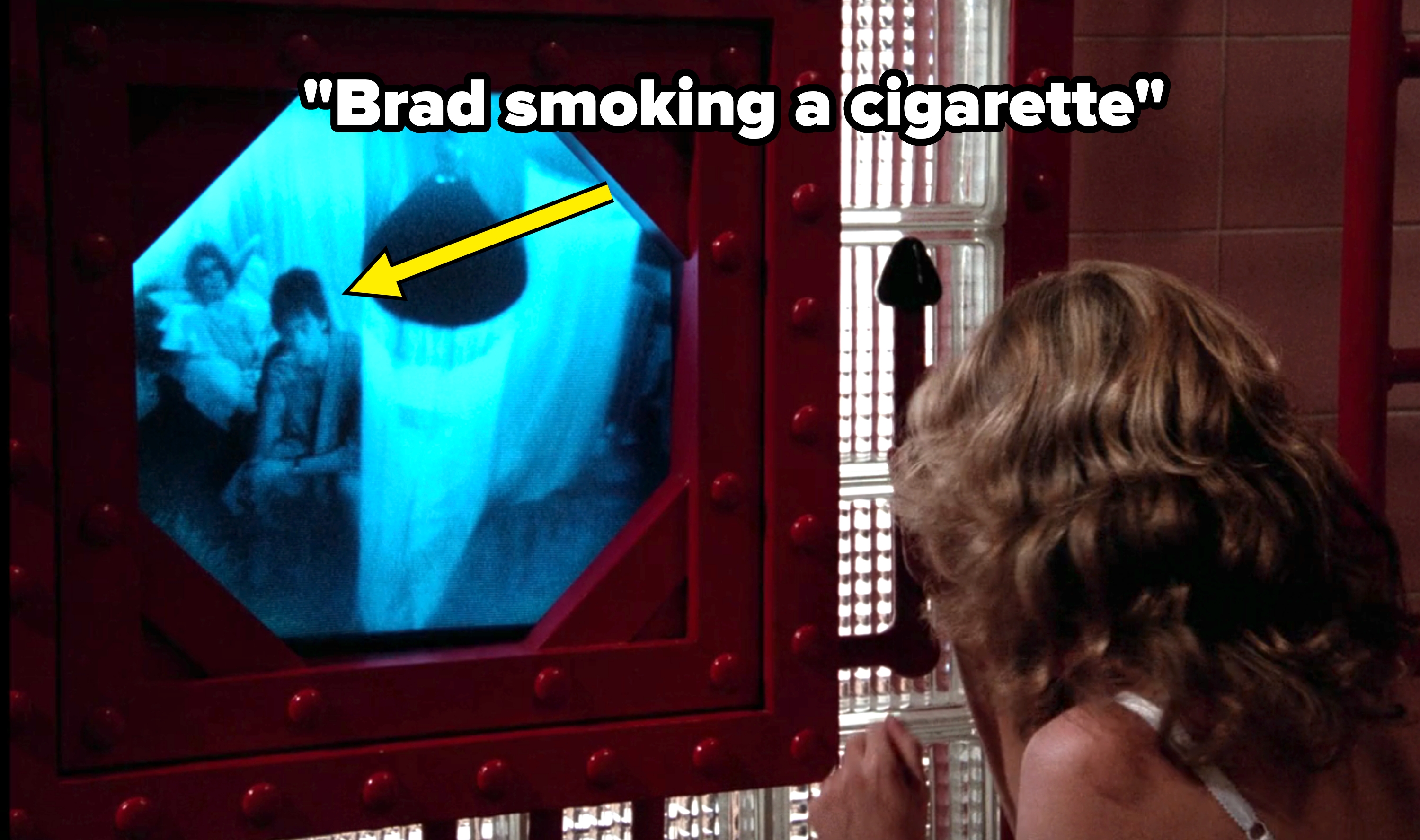 Person looks at a monitor showing two people in a dimly lit room