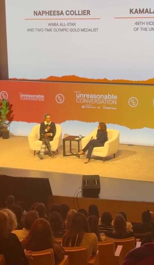 Napheesa Collier and Kamala Harris sit on stage in a panel discussion, part of the Unreasonable Conversation event. Audience members are seated below