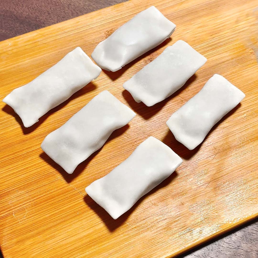 まな板にせられた6つの小さな春巻き風の食材。
