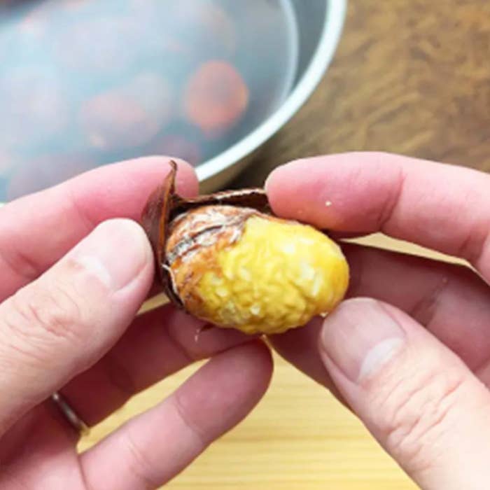 ゆでた栗の皮をむいている手元。