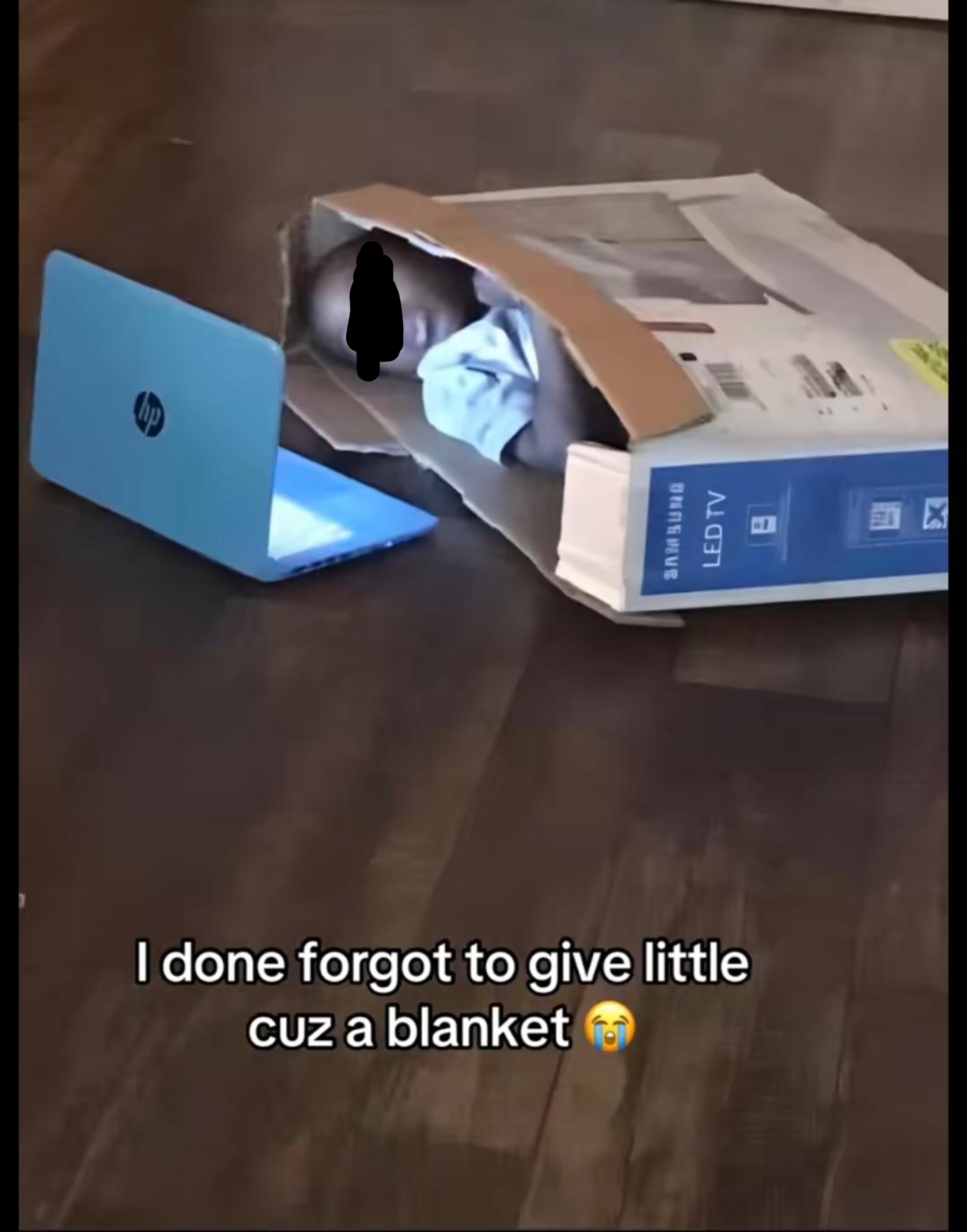 Child lying in a cardboard box next to a laptop, with text joking about forgetting to give them a blanket