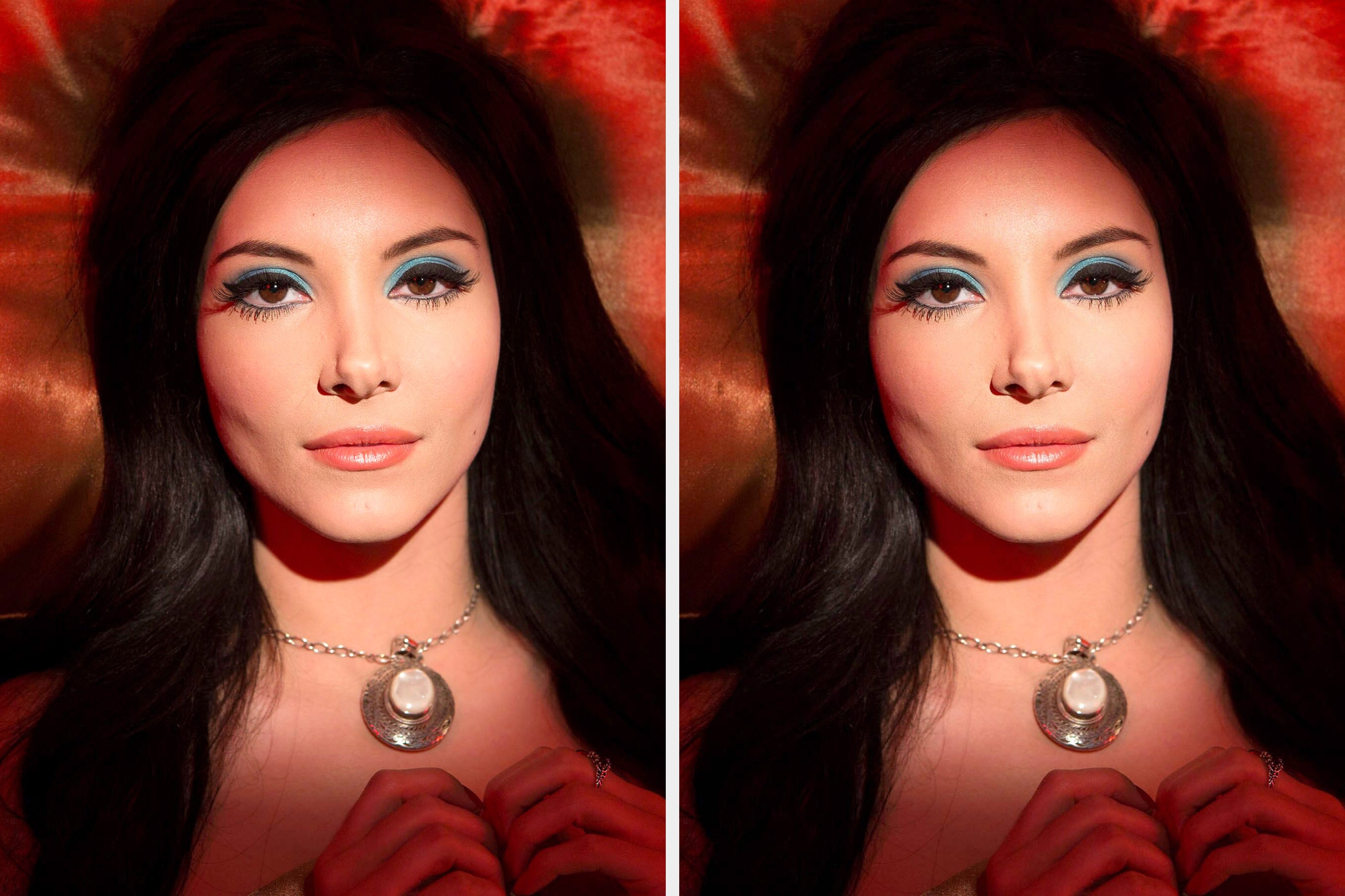 Person with long black hair and bold eye makeup, lying on a satin surface, wearing a crescent moon necklace