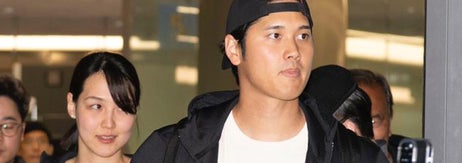 男性がカジュアルな服装で何かを見ている。周囲に数人の人々がスマホで撮影している場面。