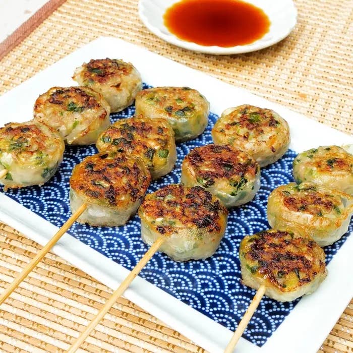 皿に盛られた焼き餃子が串に刺さって並んでおり、小皿にたれが添えられている。