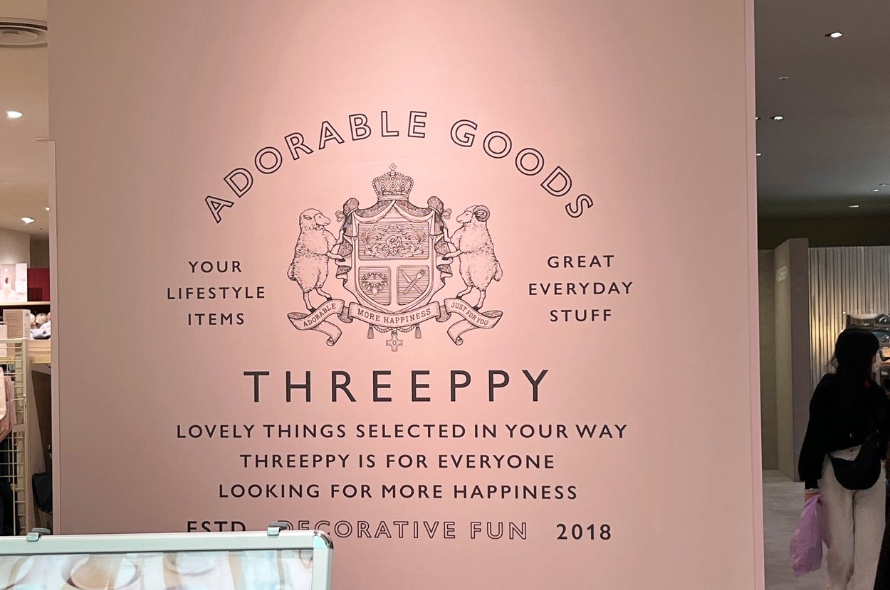 「ADORABLE GOODS THREEPPY」ロゴとコンセプトが壁に描かれた店内の光景。