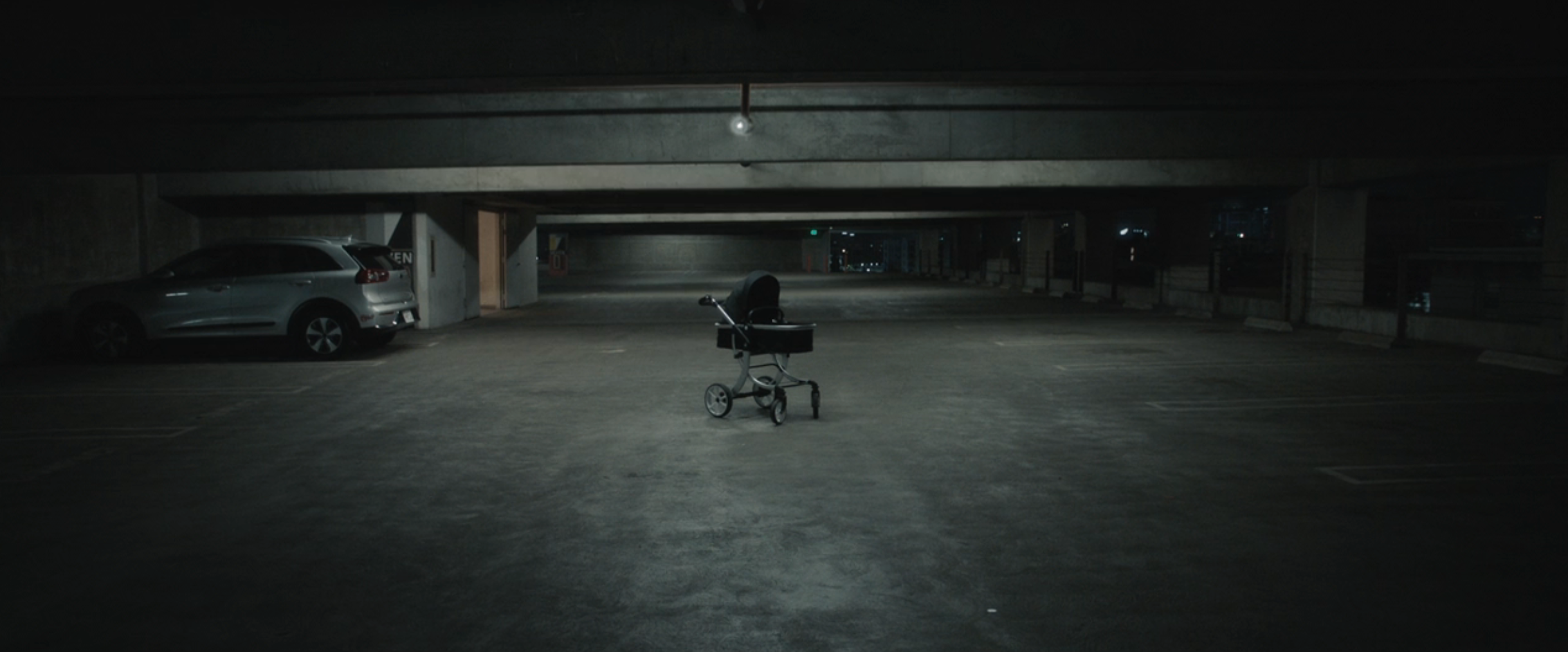 A lone stroller in an empty, dimly lit parking garage, evoking a mysterious or suspenseful atmosphere