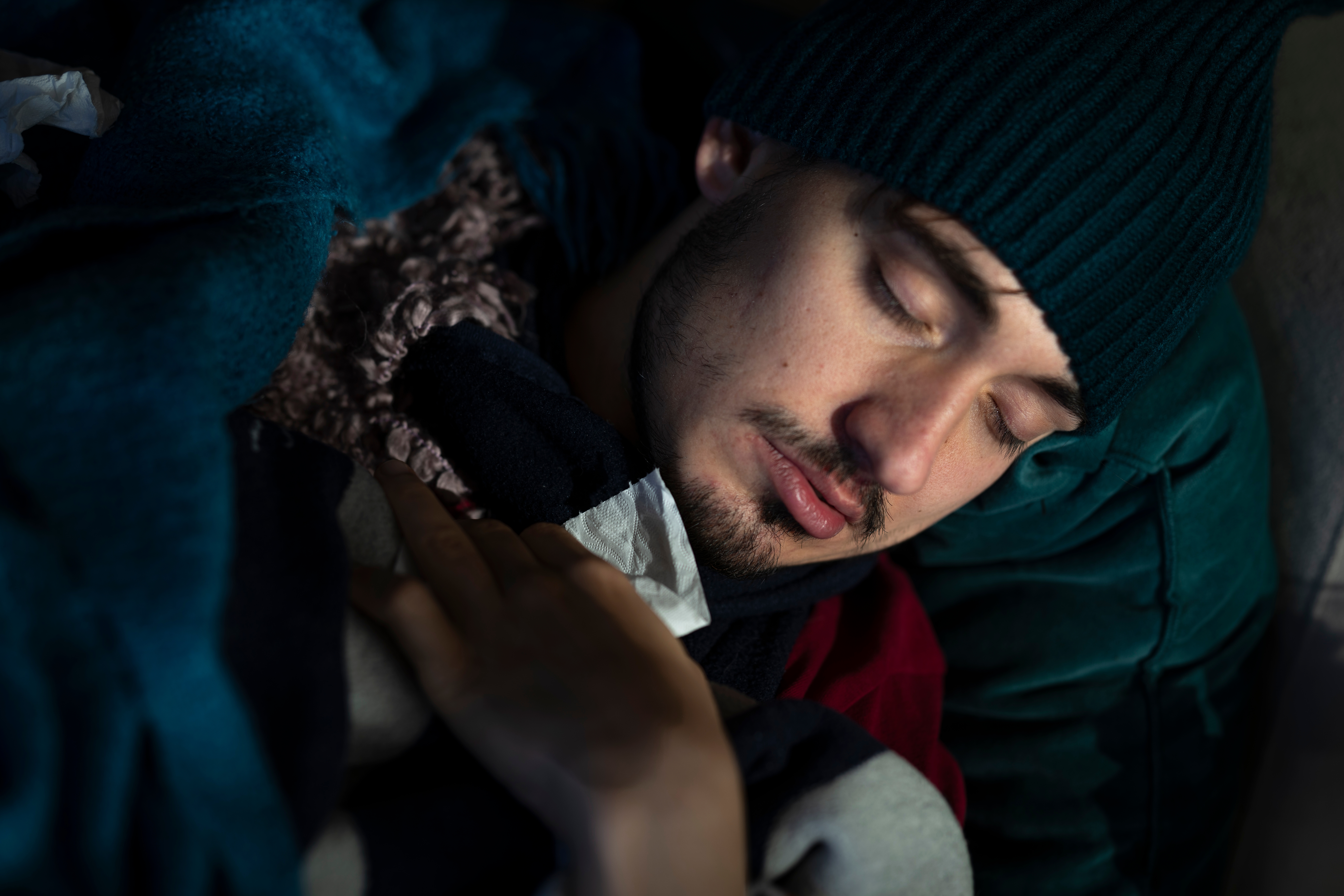 Personen som fredelig sover, pakket inn i tepper, iført en strikket hatt. Deres rolige uttrykk formidler varme og komfort