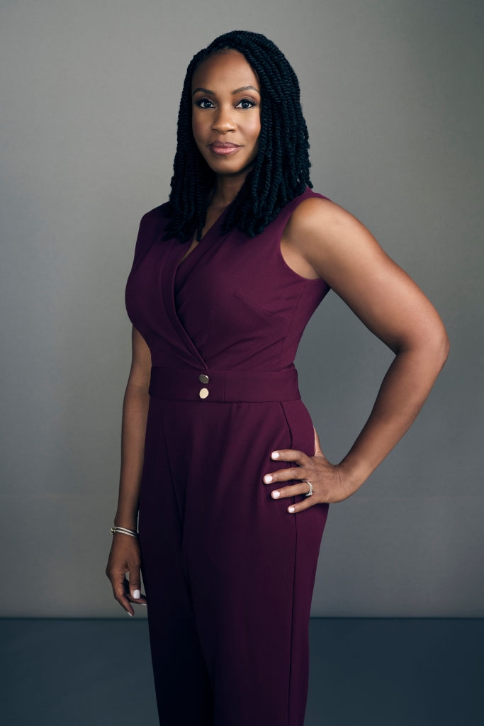 Person poses confidently in a tailored sleeveless jumpsuit, hands on hip