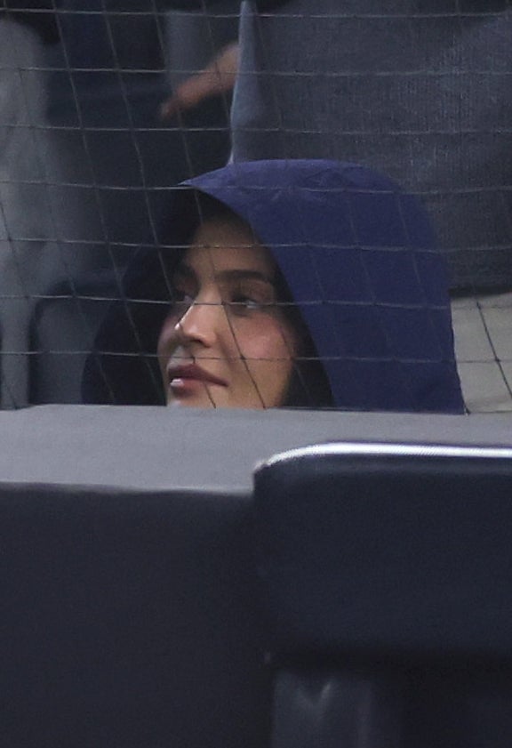 Fans cheering energetically at a baseball game, with some wearing team apparel and caps, showing excitement and support