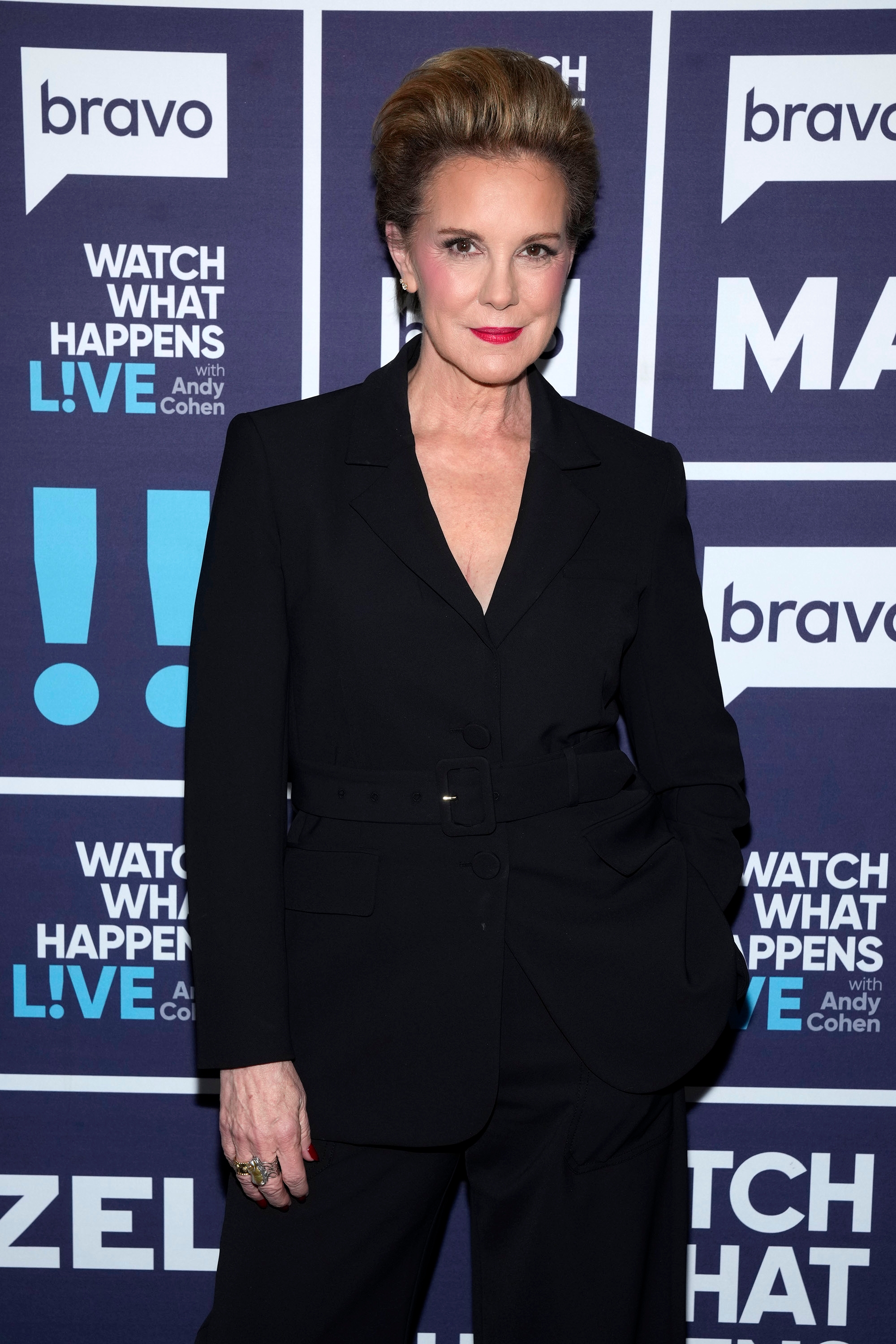 Person in an elegant, tailored black suit attending a "Watch What Happens Live" event