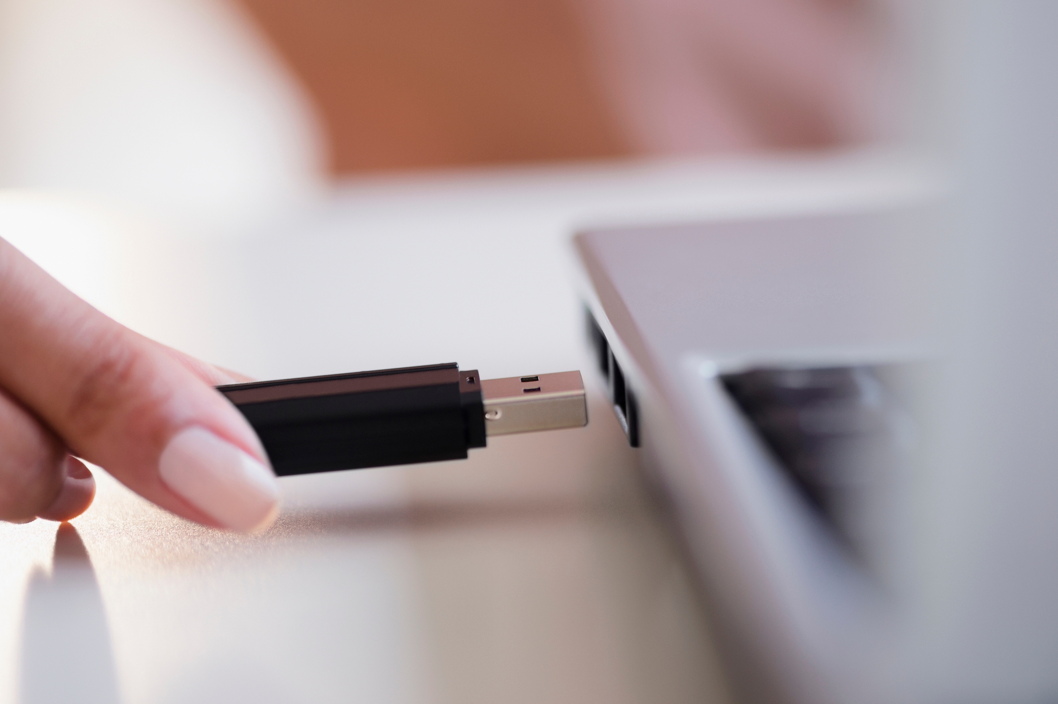 A hand is inserting a USB drive into a laptop, highlighting technology in intimate or personal contexts